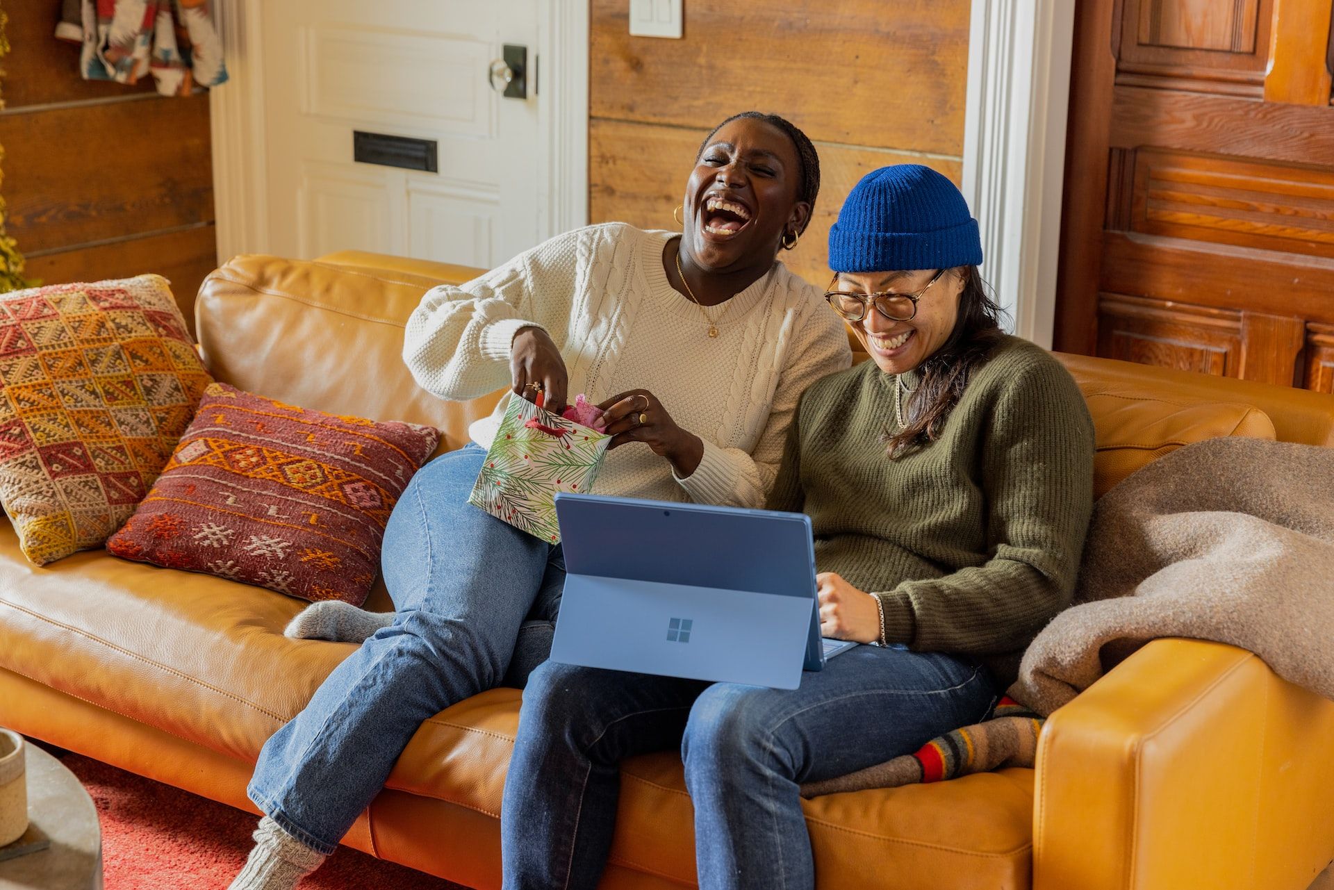 Duas mulheres dando risada enquanto olham para um notebook.